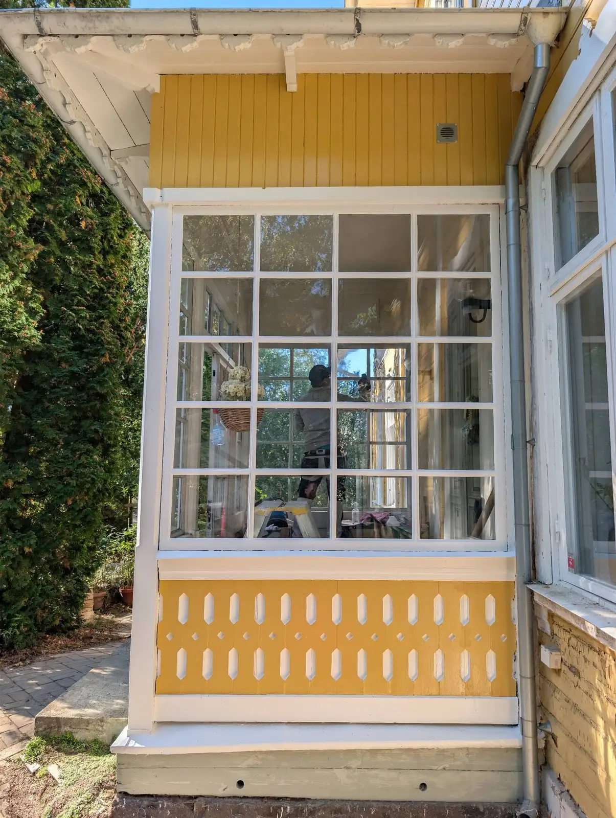 Vita spröjsade fönster på gul fasad